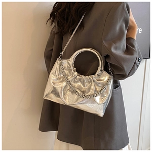Detail of silver metallic handbag featuring pleated texture and round rigid handle