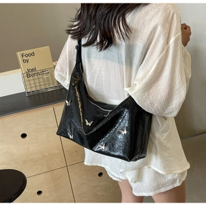 Detail of glossy black PU leather shoulder bag with silver butterfly metal decorations