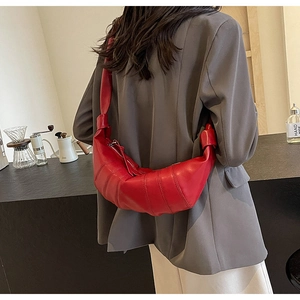 Detail of red crescent croissant bag with knot shoulder straps shown on a model