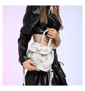 Close-up of a white mini backpack with silver butterfly patterns and a metal buckle
