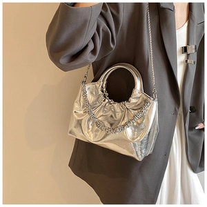 Detail of silver metallic pleated handbag with round handle and metal chain on model