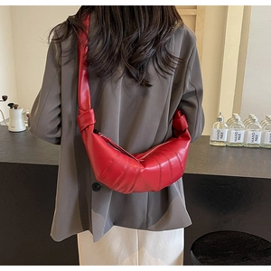 Detail shot of the red PU leather croissant bag featuring soft folds and knotted straps