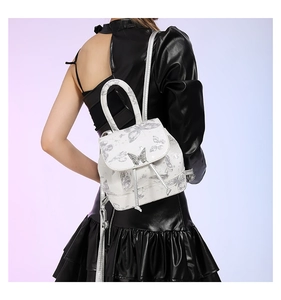 Detail of white PU backpack featuring silver butterfly print and metal clasp on flap