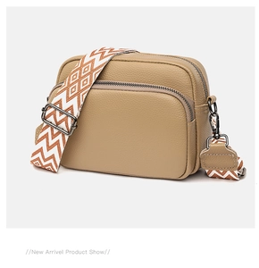 Detail of khaki litchi grain leather bag featuring a wide geometric woven shoulder strap