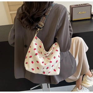 Detail of white corduroy tote bag with strawberry print and colorful woven strap