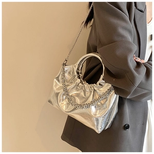 Macro detail of silver metallic pleated handbag with round handle and chain strap
