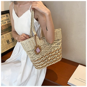 Detailed texture of two-tone straw woven tote bag with purple butterfly charm