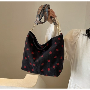 Detail of black corduroy tote with strawberry prints and ethnic style embroidered strap