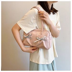 Détail d'un sac à main rose brillant orné de rubans argentés et de doubles bretelles d'épaule