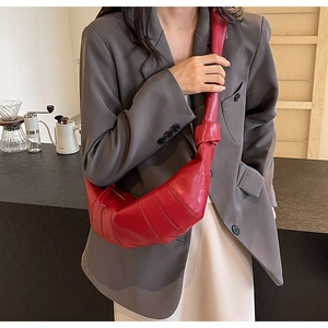 Detail of red PU leather croissant bag featuring pleated segments and knotted shoulder strap
