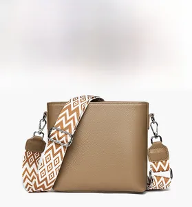 Close-up of brown lychee grain leather bucket bag with orange wave patterned wide strap