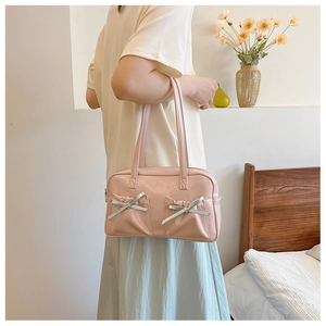 Détail d'un sac à main rose en similicuir brillant avec nœuds et poches plissées décoratives