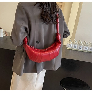 Detailed view of red PU crescent bag featuring unique pleated design and knot handle