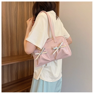 Détail d'un sac à bandoulière en cuir PU rose clair avec des nœuds argentés décoratifs