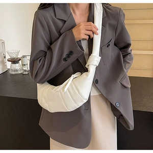 Detailed view of white PU leather croissant bag with iconic pleated segments and knot strap