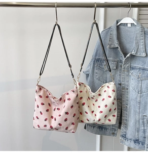Detail of strawberry print corduroy tote bags in pink and beige with adjustable straps