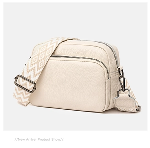 Detail of off-white lychee leather bag with wide strap and gun-black metal hardware