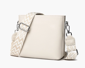 Detail of creamy white pebble grain leather bag with stylish patterned wide shoulder strap