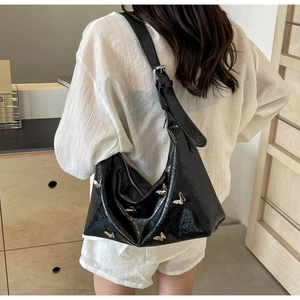 Fashionable black PU crescent bag featuring silver butterfly accents worn by a model