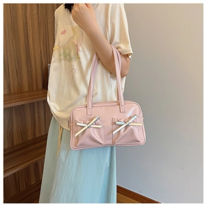 Détail du sac à main rose en cuir verni avec nœuds argentés et plis en situation réelle