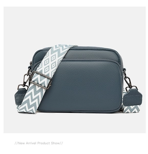 Detailed close-up of blue lychee grain leather crossbody bag with geometric woven strap