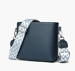Detail of navy lychee-grain leather handbag with wide blue and white woven strap
