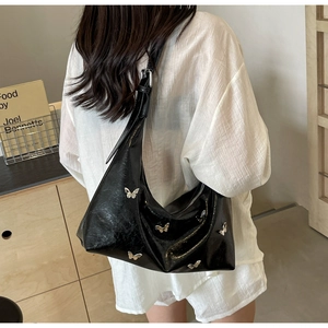 Detail shot of black hobo bag with silver butterfly charms and adjustable strap
