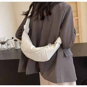 Detail view of a white croissant-style PU shoulder bag with knotted strap and segment seams