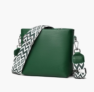 Detail view of dark green pebbled leather bag with geometric patterned wide shoulder strap