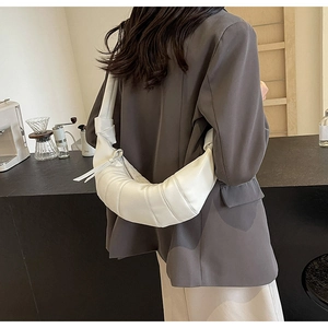 White pleated PU leather crescent crossbody bag shown on a grey suit jacket