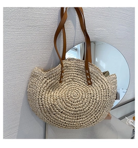 Detail of bohemian straw bag featuring woven spiral texture and brown leather strap
