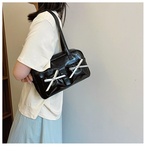 Détail d'un sac à épaule en cuir PU noir brillant avec nœuds argentés sur un modèle