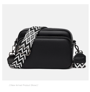 Detail of black pebbled leather crossbody bag with geometric wide strap and gunmetal hardware