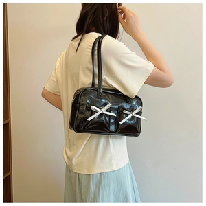 Détail du sac à main en cuir verni noir avec nœuds argentés et doubles bretelles