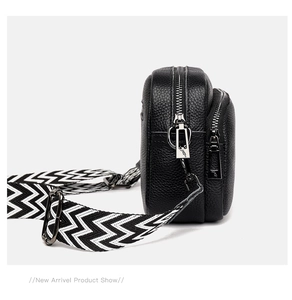 Detail view of black lychee leather crossbody bag with dual silver zippers and wide strap