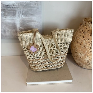Minimalist straw woven tote bag with hollow design and floral charm for spring