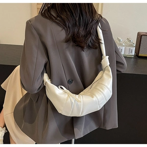 Detailed view of cream PU leather croissant bag featuring quilted panels and a knotted strap