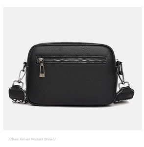 Detail view of black lychee leather bag with silver zippers and jacquard strap