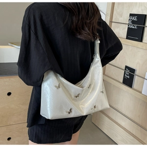 Back view of model wearing a glossy white PU leather hobo bag with butterfly details
