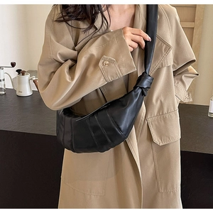 Detail of black croissant bag with pleated leather and a large knotted shoulder strap