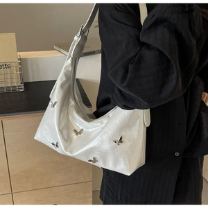 Close-up of white semi-circle PU bag with silver butterfly metallic charms on person