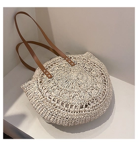 Detail of handwoven straw tote featuring hollow pattern and brown leather straps