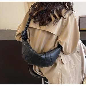 Detail of black PU leather croissant bag featuring pleated design and knotted shoulder strap