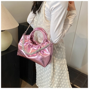 Pink metallic crossbody bag with silver chain detail on model in home setting