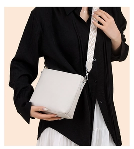 Detail view of cream-white leather crossbody bag featuring a chic chevron pattern wide strap