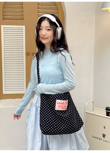 Detailed close-up of retro black polka dot canvas tote bag with pink square logo patch
