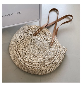 Detail of beige straw bag showing circular woven texture and brown leather straps