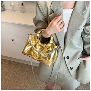 Detail of a shiny metallic gold cloud bag with silver chain strap on a blazer