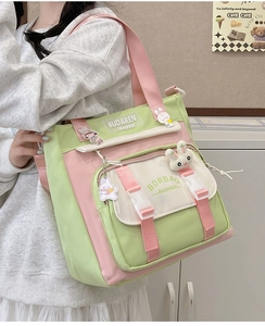 Detail of cute nylon crossbody bag with cartoon badges and pink-green color block