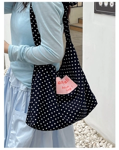 Detailed side view of large capacity black polka dot canvas tote with pink text patch